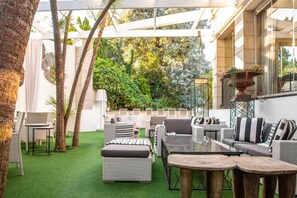 An outdoor patio area with wicker furniture, a glass table, and a green artificial turf.