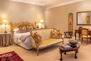 A hotel room with a bed, a sofa, a small table, a chair, a mirror, and a carpeted floor. - The Fairlawns Boutique Hotel & Spa (Johannesburg)