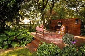 Un espace extérieur aménagé avec une terrasse en bois, deux chaises, une table et un banc.