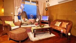 A cozy living room with wicker furniture, a television, and a balcony with a view. - Yilan Yalu Good View Homestay (Datong)