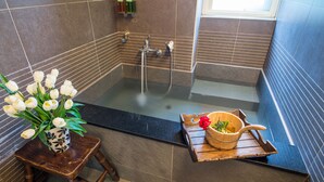 A bathroom with a bathtub, a wooden stool with a bowl, and a vase of flowers. - Yilan Yalu Good View Homestay (Datong)