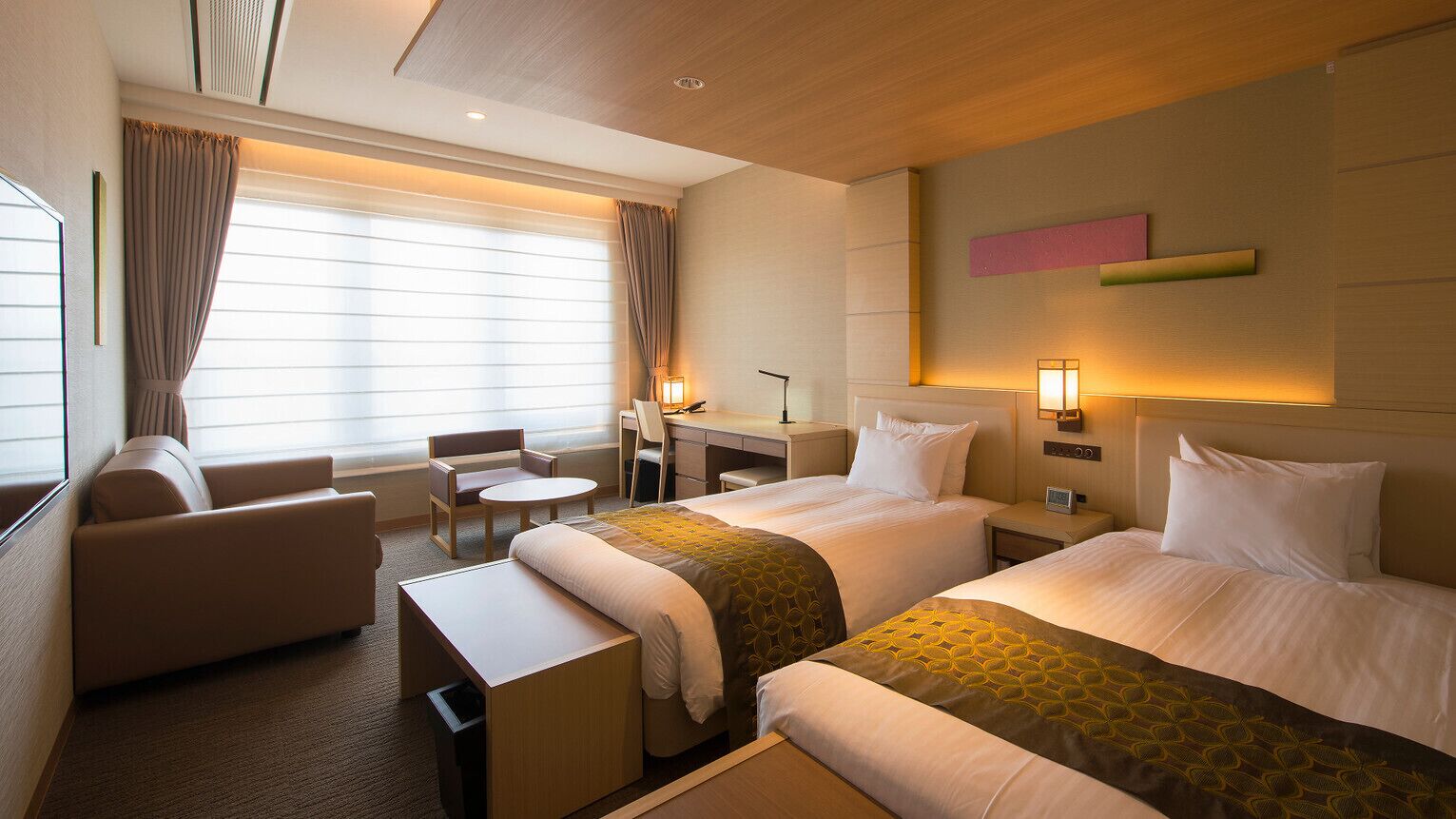 Une chambre d’hôtel avec deux lits, un bureau, une chaise et un canapé.