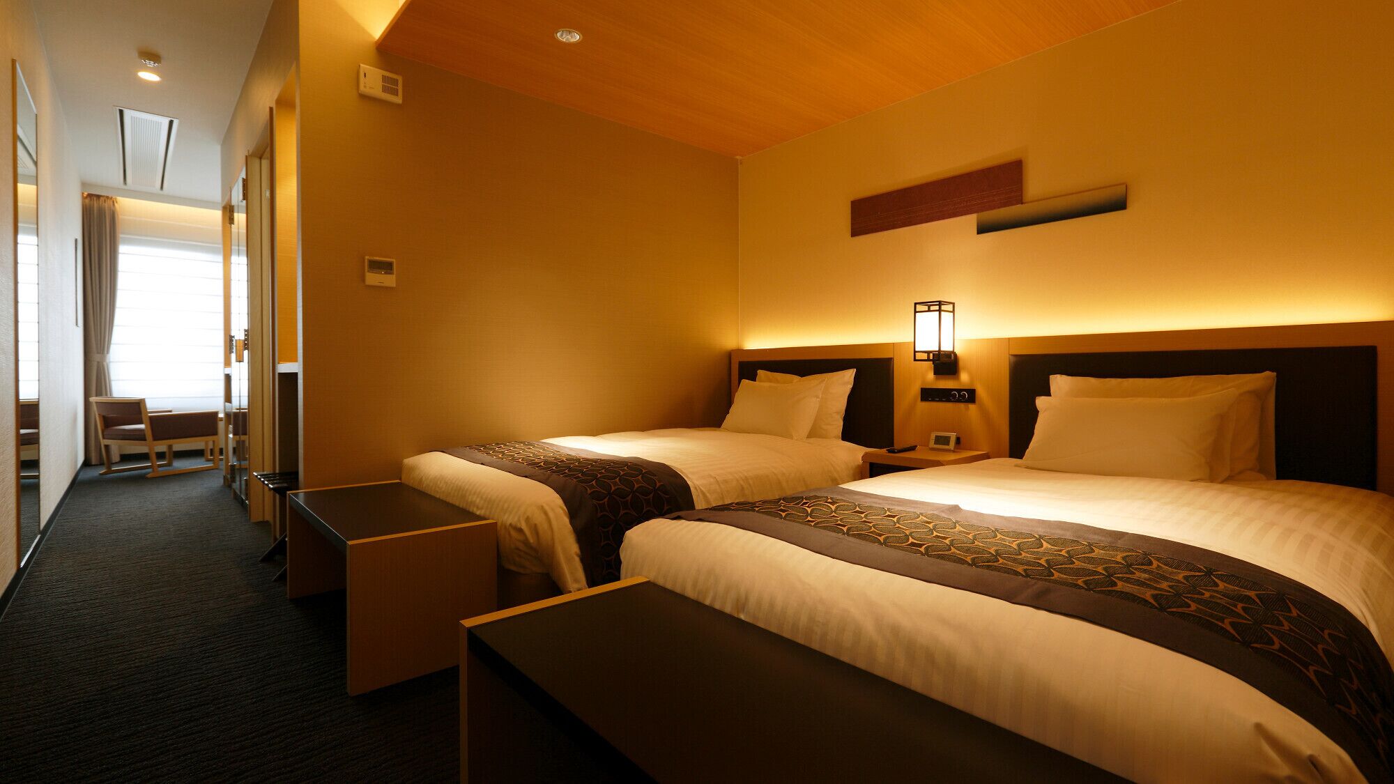 Une chambre d’hôtel avec deux lits, un bureau, une chaise et une table de chevet.
