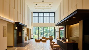 A spacious hotel lobby with a high ceiling, large windows, and a central seating area. - The Kanazawa Sainoniwa Hotel (Kanazawa)