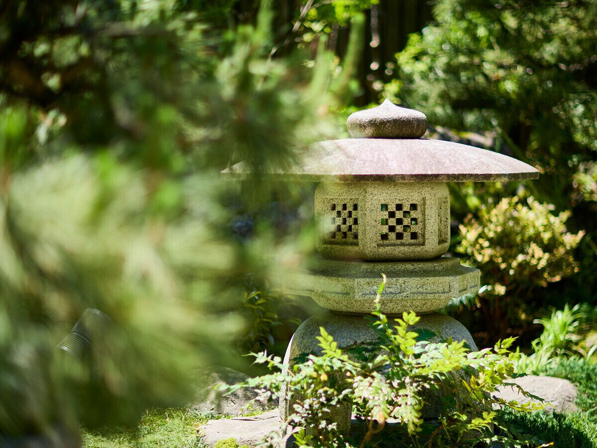 A stone pagoda with a checkered pattern, surrounded by lush greenery.