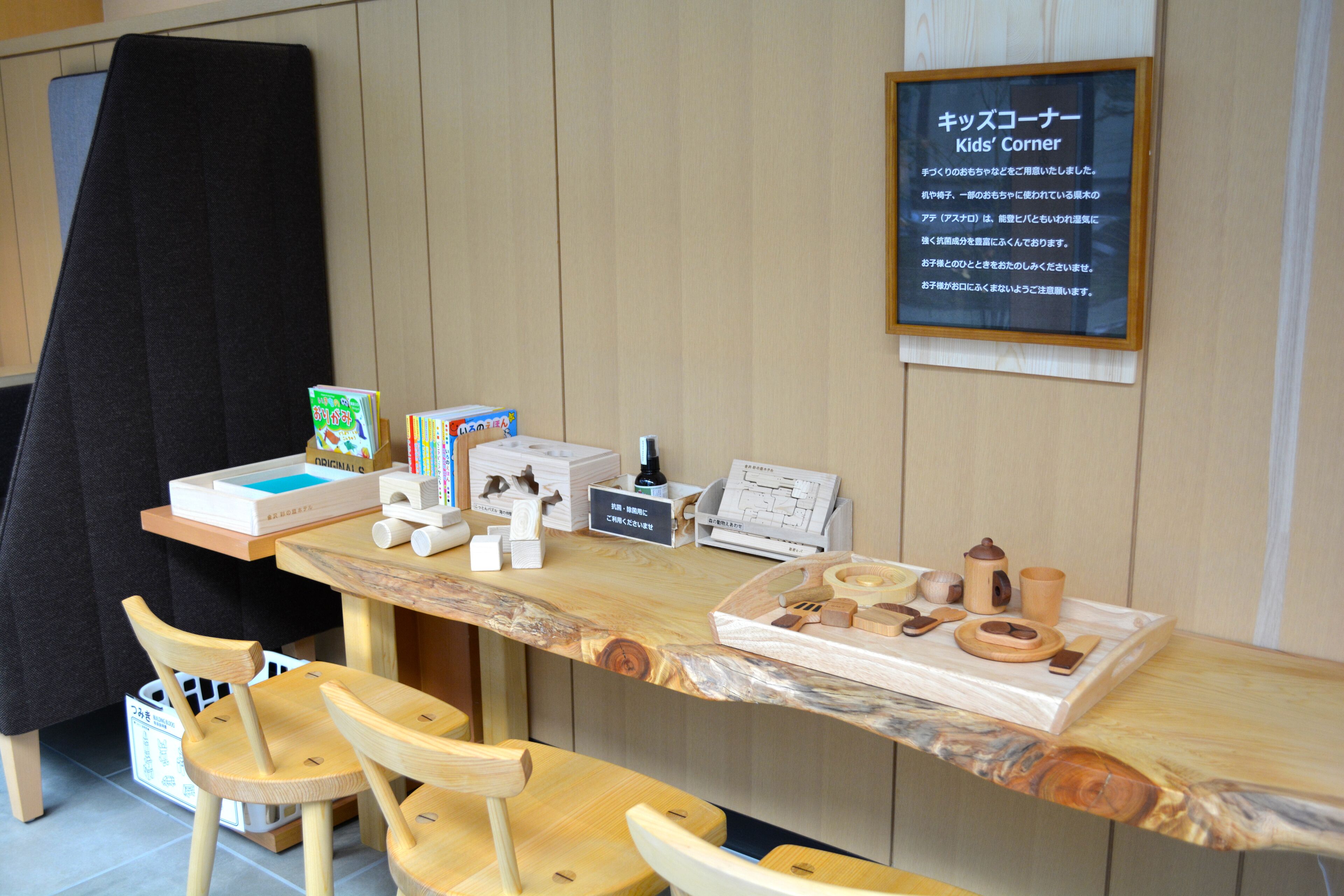 A children's corner with educational toys and books, wooden chairs, and a signboard.