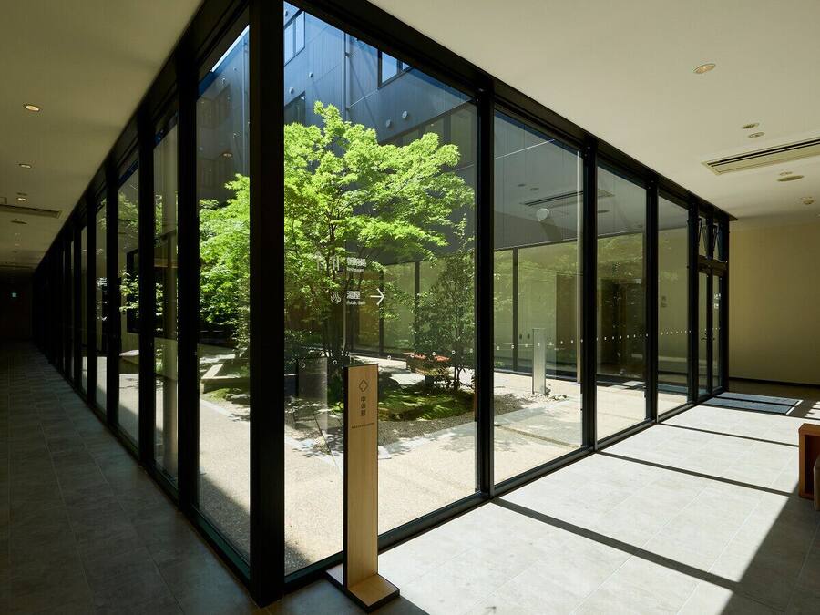 A modern interior with large glass windows, a tiled floor, and a wooden sign.