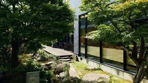 A garden with a wooden deck, rocks, and a sign. - The Kanazawa Sainoniwa Hotel (Kanazawa)