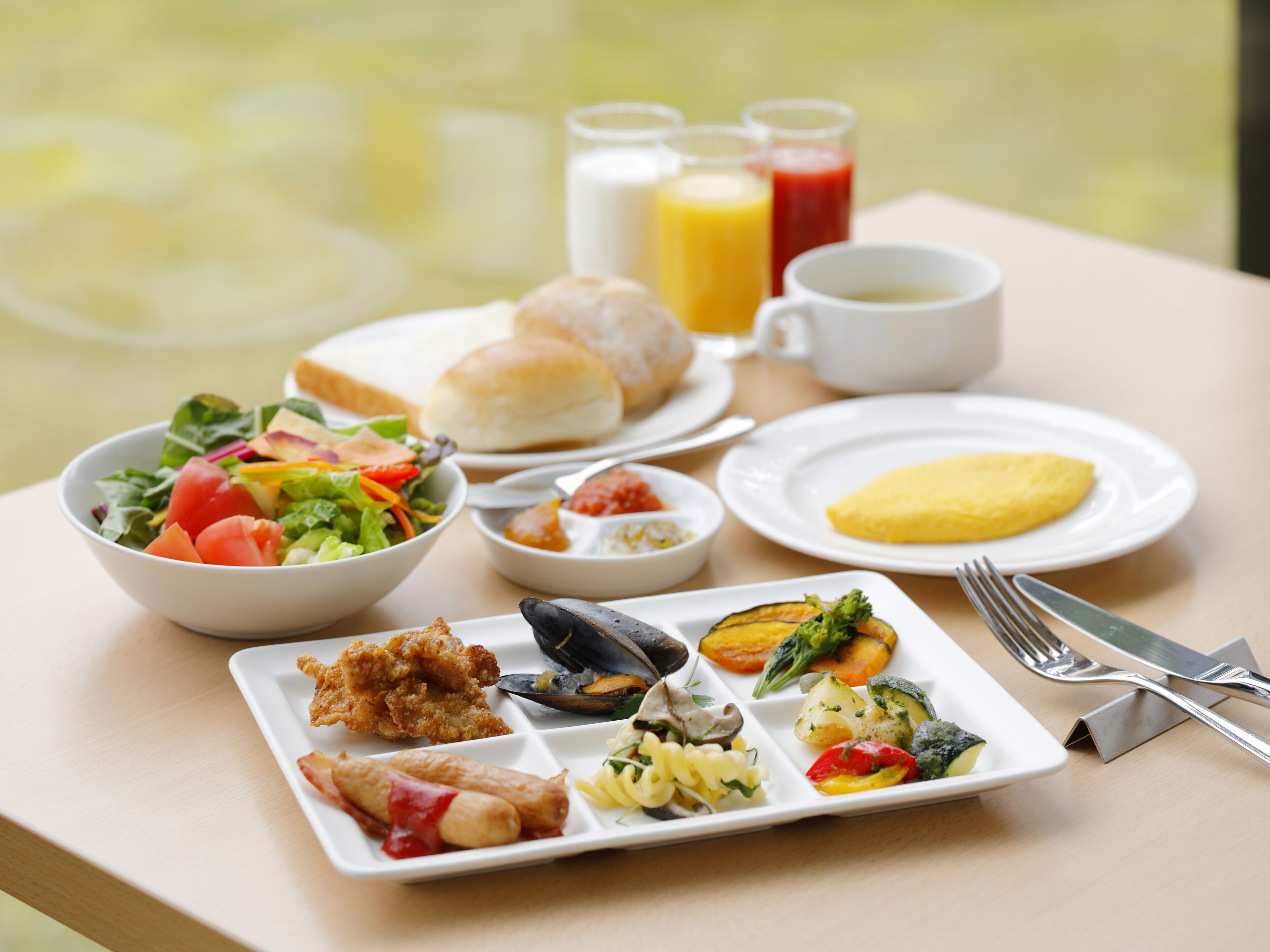 A table with a variety of breakfast items including eggs, bread, and a salad.