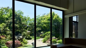 A modern interior with large windows, a wooden bench, and a glass table. - The Kanazawa Sainoniwa Hotel (Kanazawa)