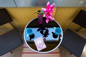 Une table ronde ornée d’un vase de fleurs, de deux tasses et d’un livre.