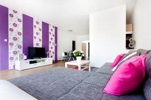 A modern living room with a grey sofa, a white entertainment unit, and a television. - Grand Budapest Apartments (Budapest)