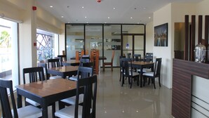 A modern dining area with multiple tables and chairs, large windows, and a view of the outside. - Sumo Asia Hotels - Davao (Davao)