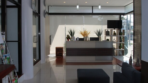 A modern reception area with a glass partition, a reception desk, and a flat-screen TV. - Sumo Asia Hotels - Davao (Davao)