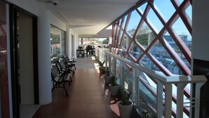 A corridor with benches and potted plants, leading to a dining area with tables and chairs. - Sumo Asia Hotels - Davao (Davao)