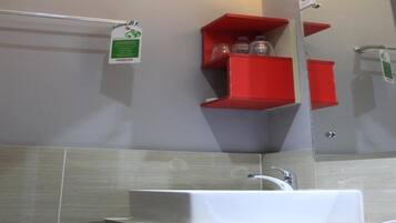 A bathroom with a white sink, a mirror, and red storage shelves.
