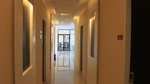 A corridor with doors on both sides, leading to a bright room with a glass door at the end. - Sumo Asia Hotels - Davao (Davao)