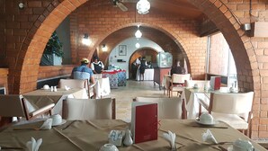 A restaurant with brick arches, tables set with white tableware, and a Christmas tree in the background. - The Lusaka Hotel (Lusaka)