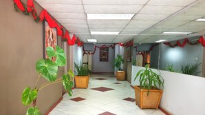 A hallway with tiled flooring, potted plants, and red decorations. - The Lusaka Hotel (Lusaka)