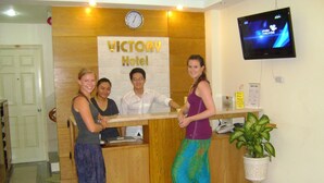 A reception desk at Victory Hotel with a clock, a TV screen, and a potted plant. - Marie-Line Hotel (Ho Chi Minh City)