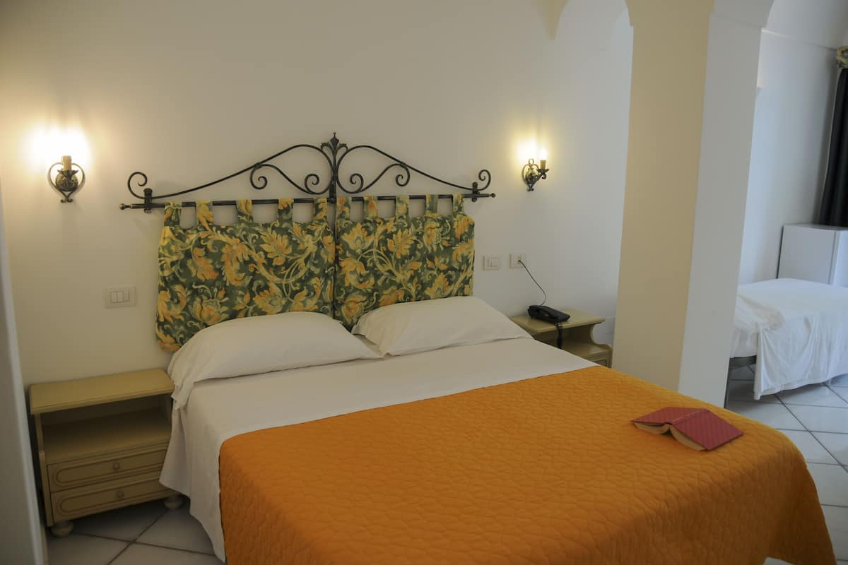 A neatly made bed with an orange bedspread, a floral headboard, and two wall-mounted reading lamps.