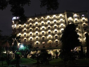 A multi-story hotel with a symmetrical facade, evenly spaced balconies, and a well-lit entrance area.