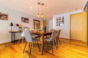 Un comedor con mesa de madera, sillas tapizadas en gris, lámpara colgante y obras de arte en la pared.