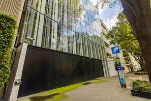 En moderne bygning med en spejlvendt glasfacade, et parkeringsskilt og en fortov.