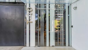 A modern building entrance with a glass door, a metal number plate, and a concrete step.