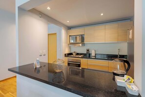 Una cocina moderna con encimera negra, electrodomésticos de acero inoxidable y armarios de madera.