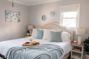 A bedroom with a bed, bedside tables, a window, and wall decorations.