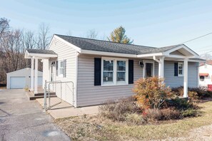 A single-story house with a covered porch, a garage, and a small front yard with shrubs.