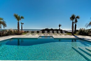 A pool with clear blue water, surrounded by lounge chairs and palm trees, with a view of the ocean. - Discounts! Sea Spray- 400 Ocean Blvd. Oceanfont! Six Bedroom, Sleeps 15, Private Pool/Hot Tub (Isle Of Palms)