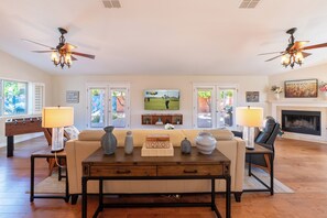 A spacious living room with a sofa, coffee table, and fireplace. - The Wildflower Oasis by HomeSlice Stays (Scottsdale)