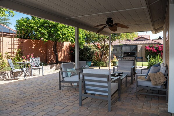 An outdoor patio with patio furniture, a ceiling fan, and a view of the backyard. - The Wildflower Oasis by HomeSlice Stays (Scottsdale)