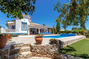 Une villa dotée d’une piscine, d’un escalier en pierre et d’une façade bleue et blanche.