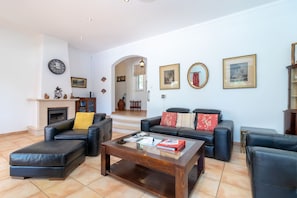 Ein Wohnzimmer mit Ledersofas, einem Couchtisch, einem Kamin und gerahmten Bildern an der Wand.