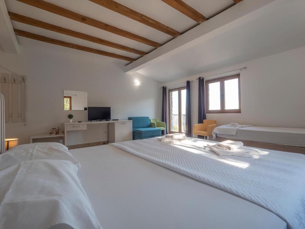 Una habitación de hotel con una cama grande, un escritorio con computadora, un televisor y dos sillas.