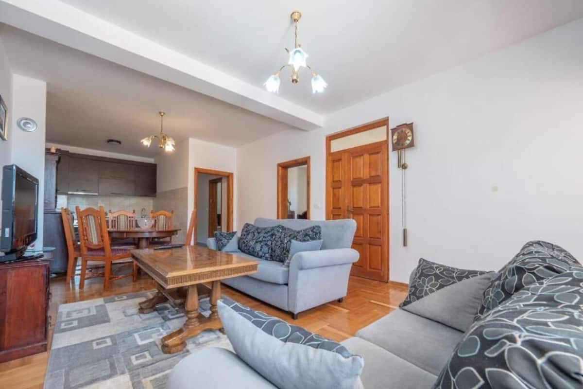 A living room with a sofa, a dining table, and a TV.