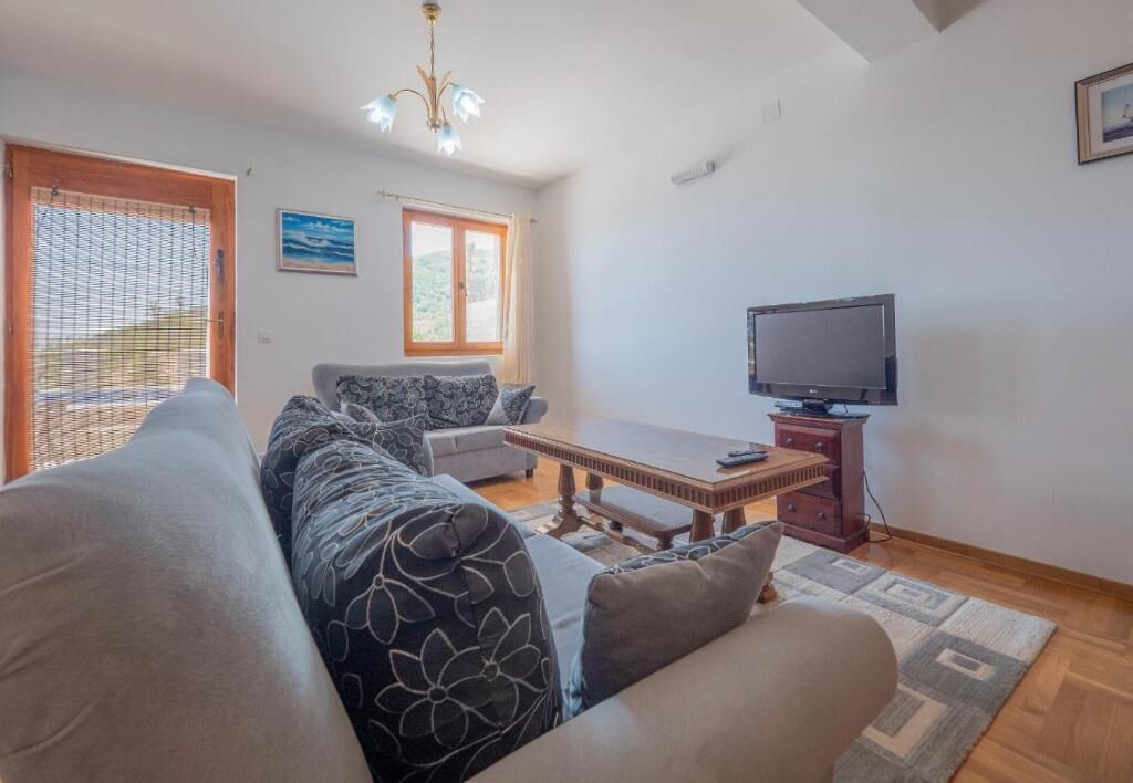 Una sala de estar con un sofá, un sillón y un televisor sobre un mueble de madera.