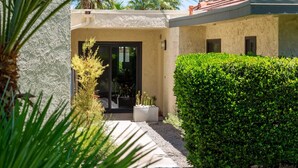 A modern building with a beige facade, a black door, and a well-maintained green hedge. - Riviera Gardens Minutes from Downtown (Palm Springs)