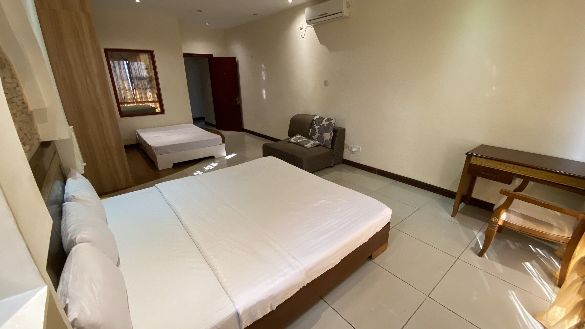 Une chambre d’hôtel avec un grand lit, un petit canapé, une table en bois et un tableau au mur.