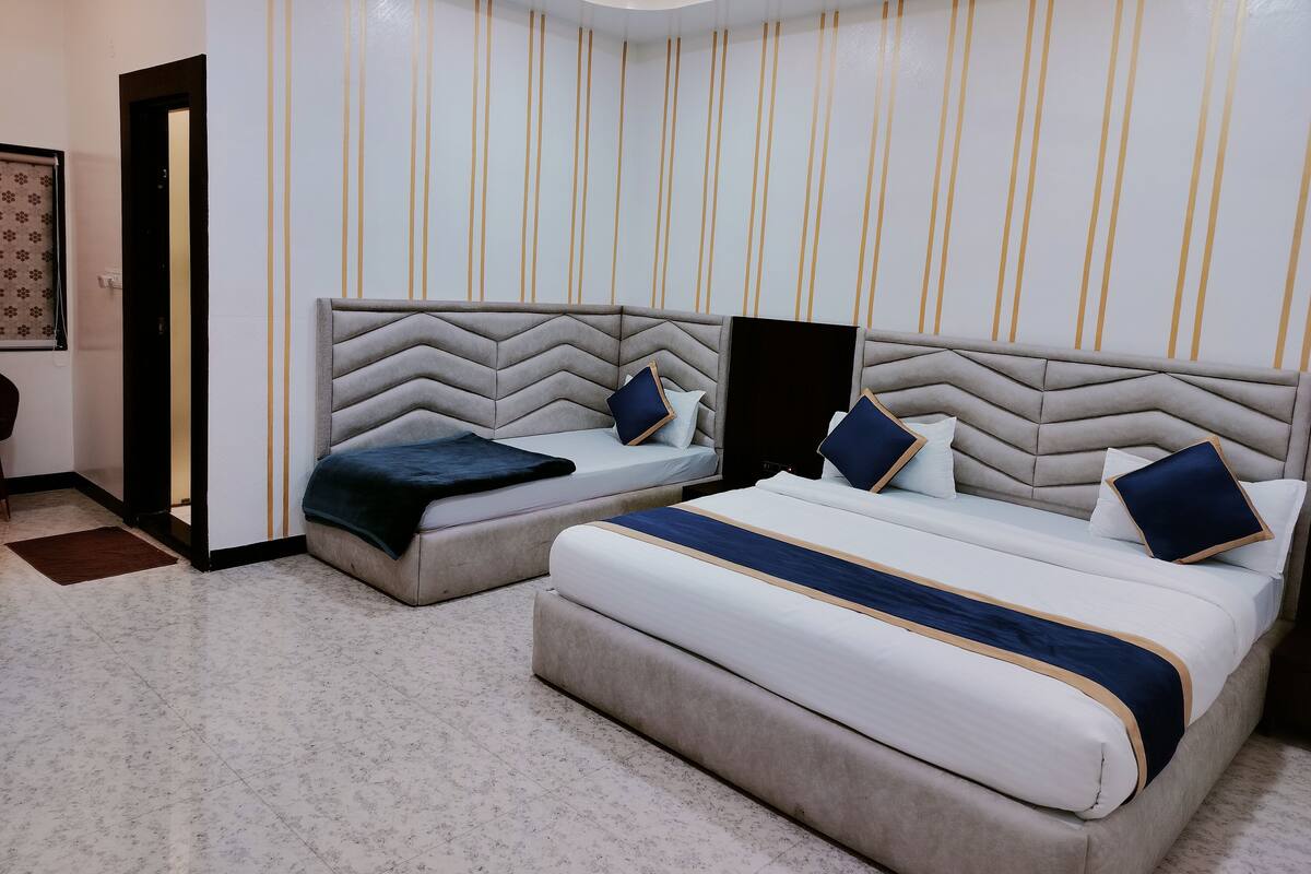 A hotel room with two beds, a large mirror, and a patterned wall.