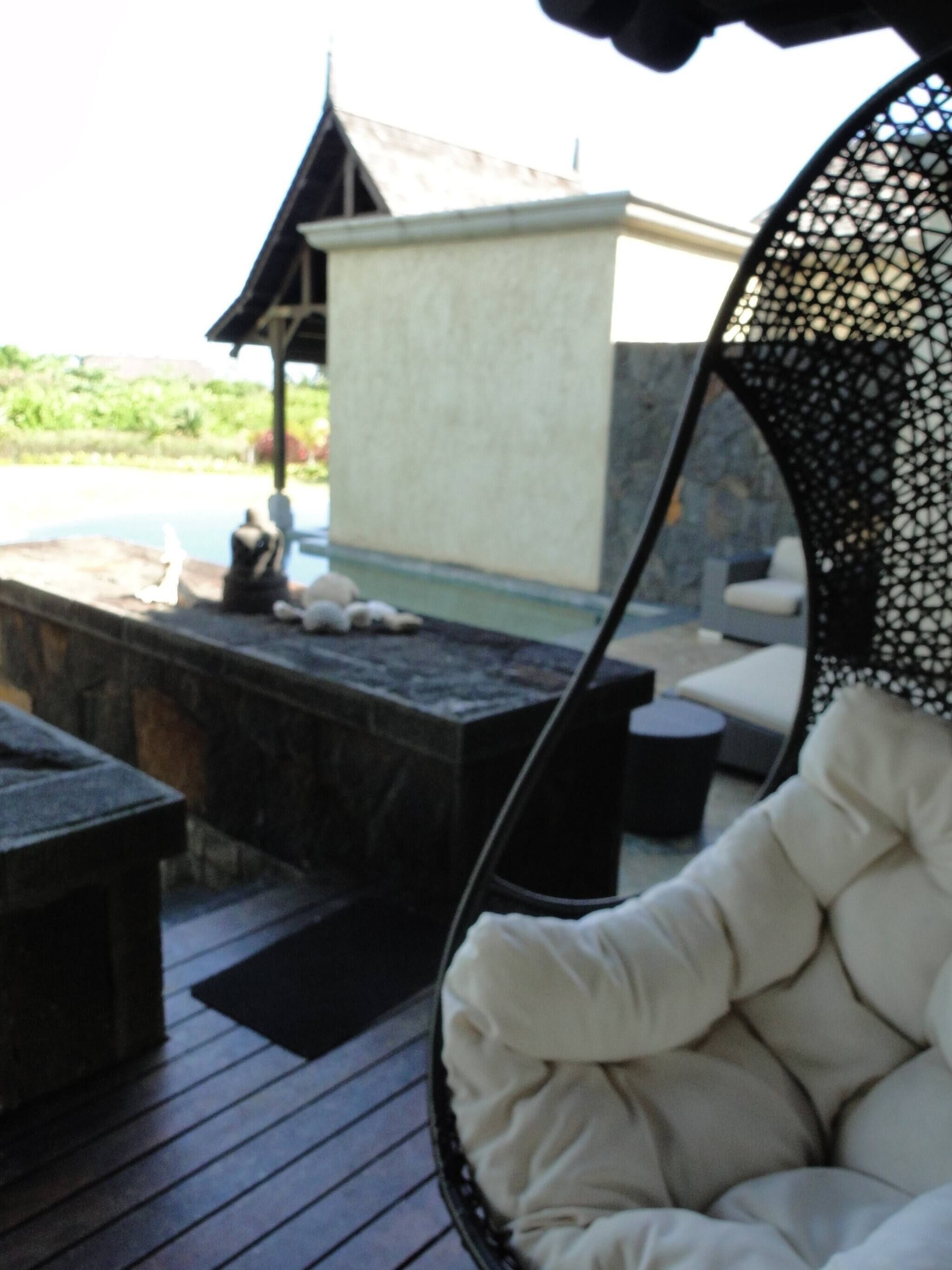 A wooden deck with a white cushioned chair, a stone bench, and a small table.