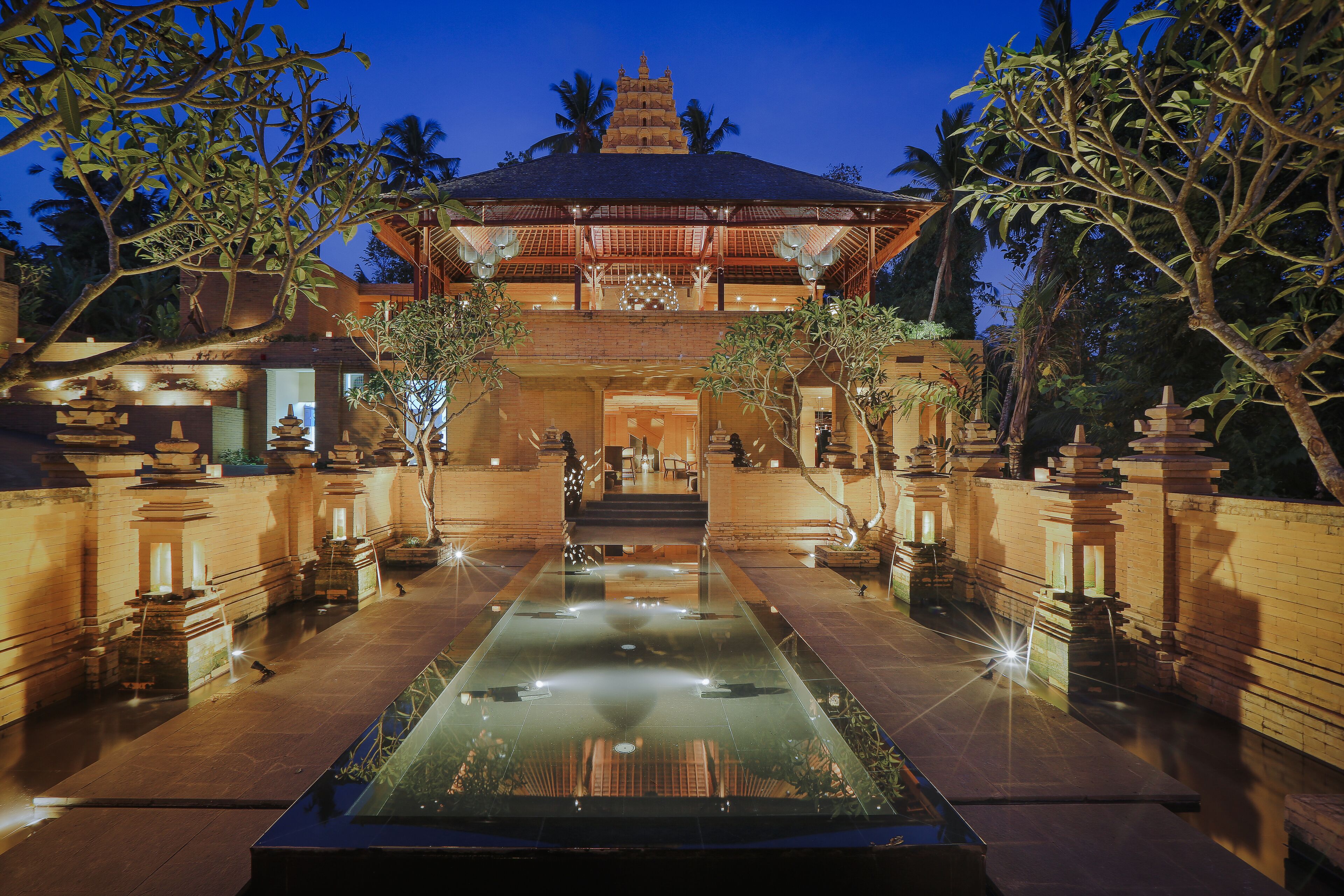 A traditional building with a central water feature, surrounded by stone walls and palm trees.