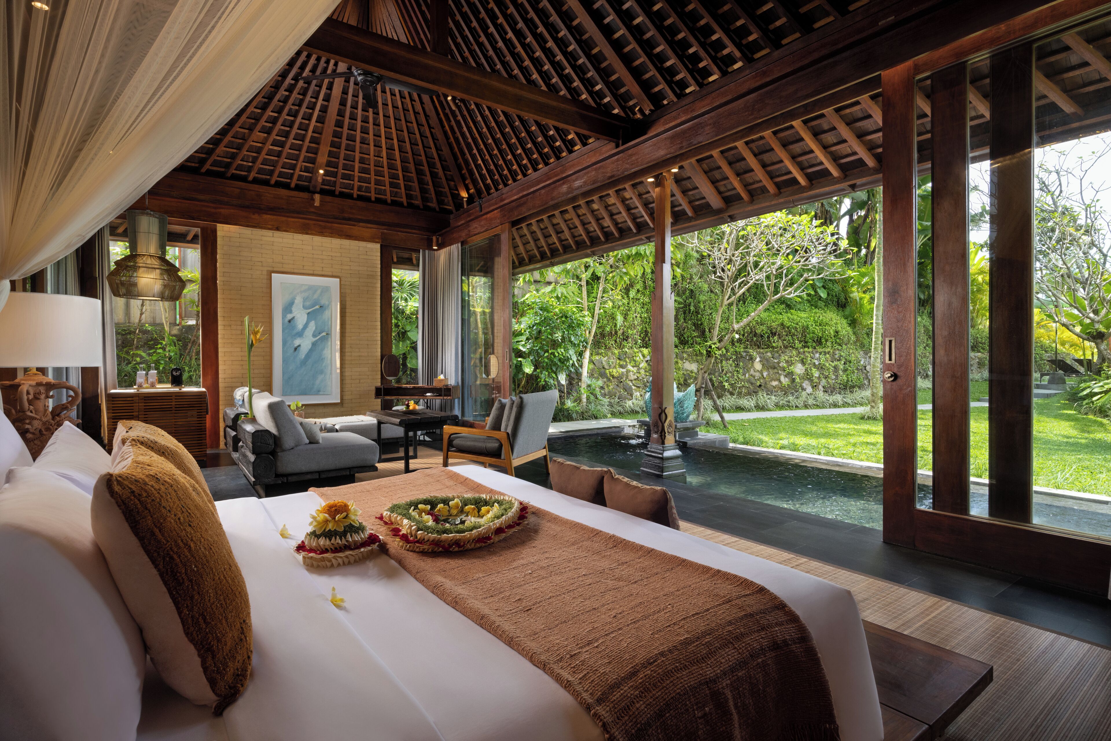 Une chambre spacieuse avec un grand lit, une table à manger et une vue sur un jardin luxuriant et une piscine.