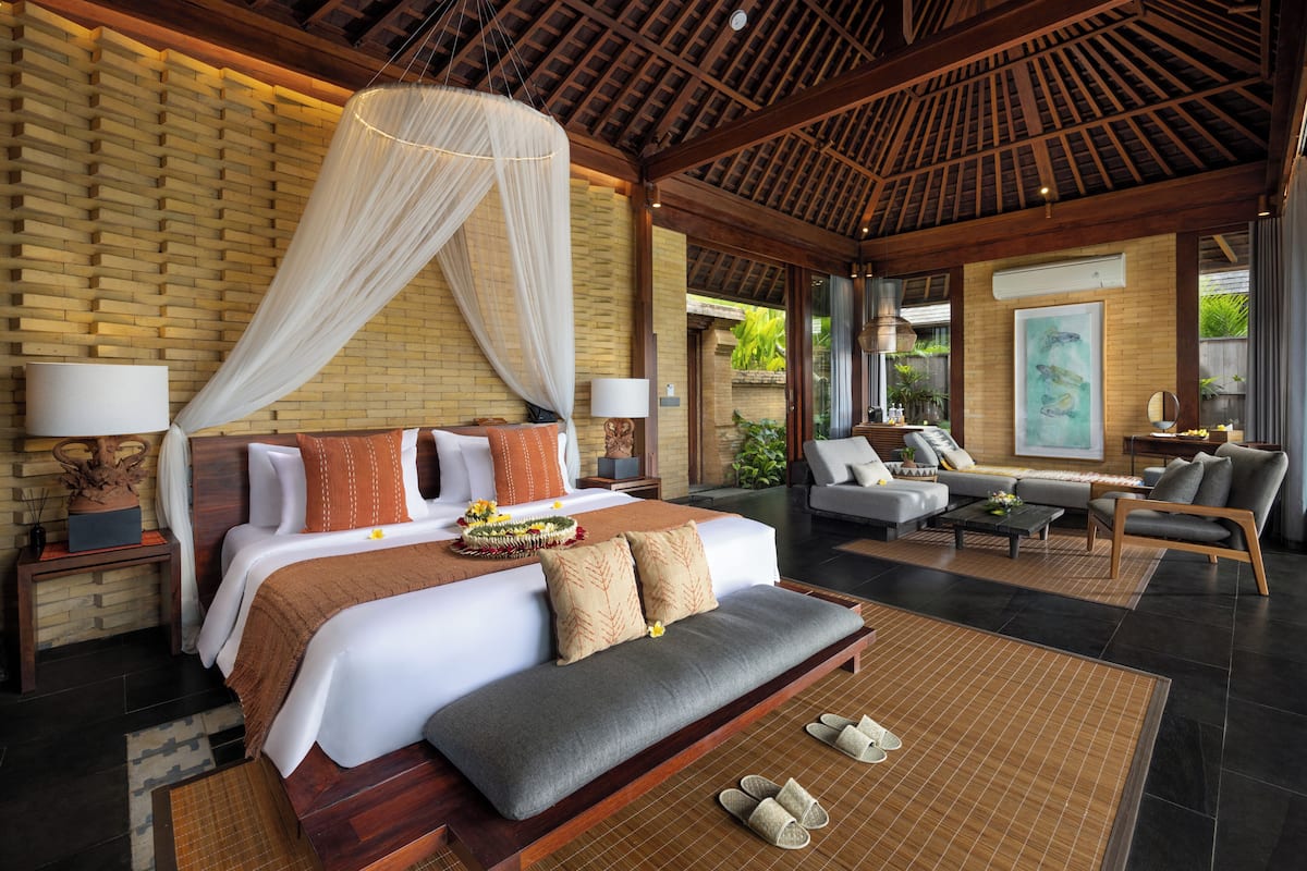 A spacious bedroom with a large bed, a sofa, and a dining area.