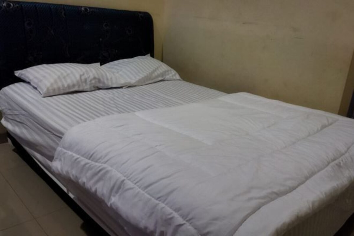 A single bed with a dark headboard and white bedding.