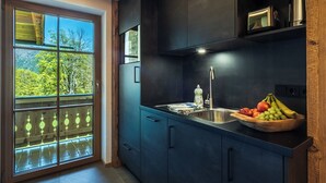 A modern kitchen with dark cabinetry, a stainless steel sink, and a bowl of fruit on the counter. - Appartement Kehlstein für 2 Personen, 38qm mit Balkon (Schönau am Königssee)