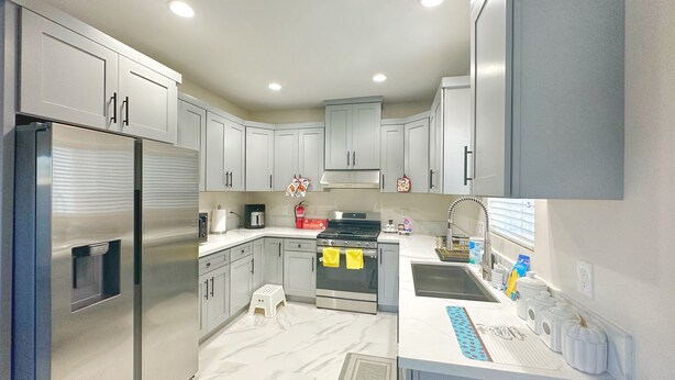 A modern kitchen with grey cabinets, stainless steel appliances, and a marble countertop. - Guesthouse near Anaheim Convention (Santa ana)
